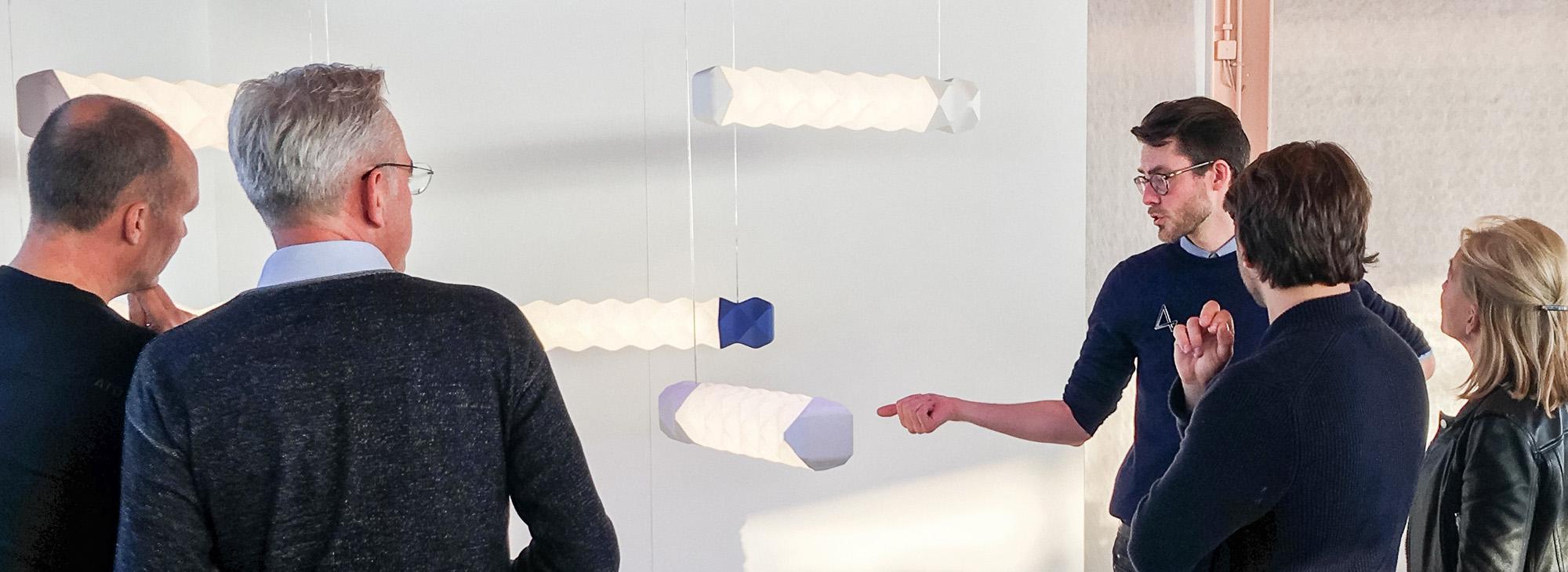 Erik Stehmann (derde van rechts) vertelt over zijn Rilly Nice lampen